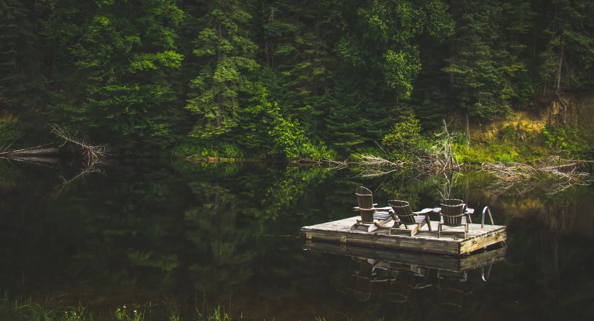 Rustic dock with Muskoka chairs on a calm forest lake in Bracebridge, Ontario
