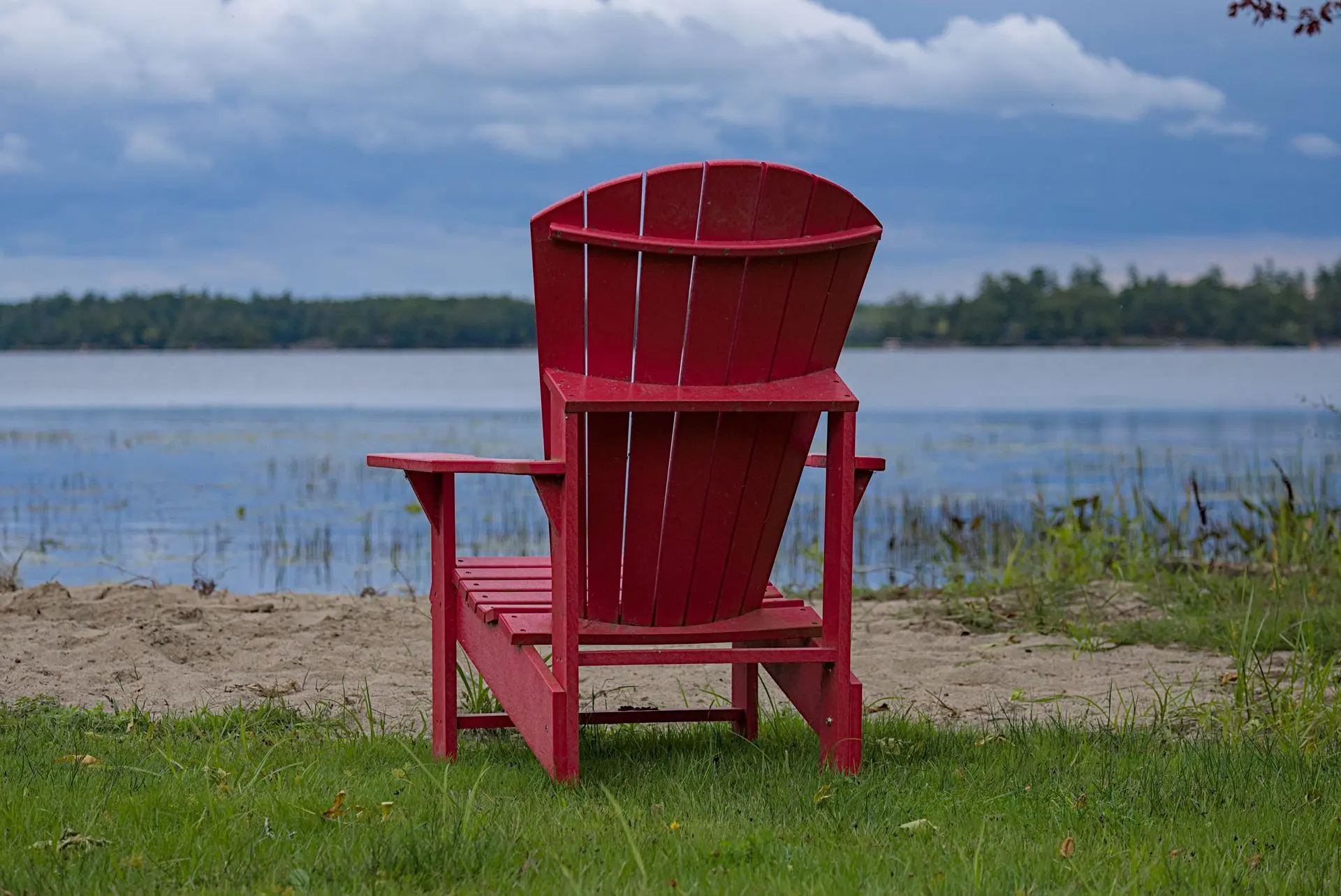 Red Muskoka chair on a dock overlooking a serene Ontario lake